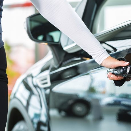 Young woman and seller with auto in car dealership